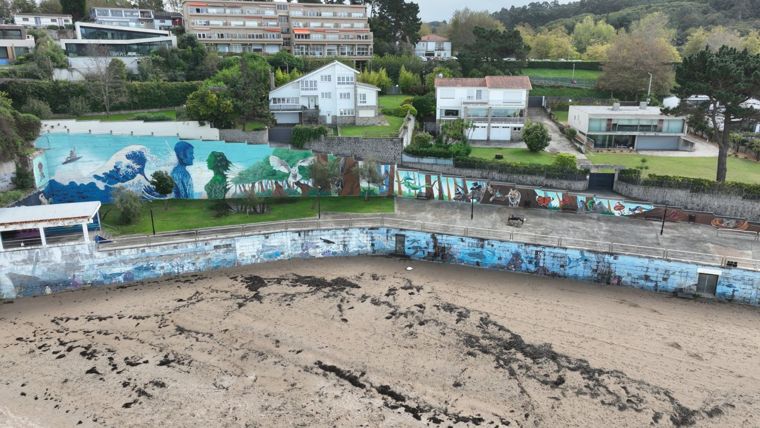 Turquesa: mural en el muro de la playa de Bastiagueiro, con una gran ola, un hombre azul y una mujer verde frente a frente, una lechuza y un bosque con animales